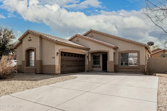 mediterranean / spanish house featuring driveway, an attached garage, a tiled roof, and stucco siding