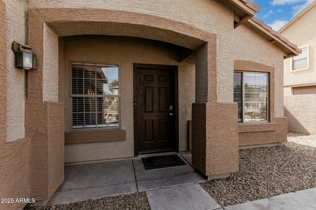 property entrance with a tile roof and stucco siding