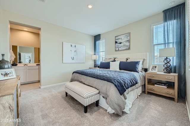 bedroom featuring light colored carpet, baseboards, recessed lighting, and ensuite bath