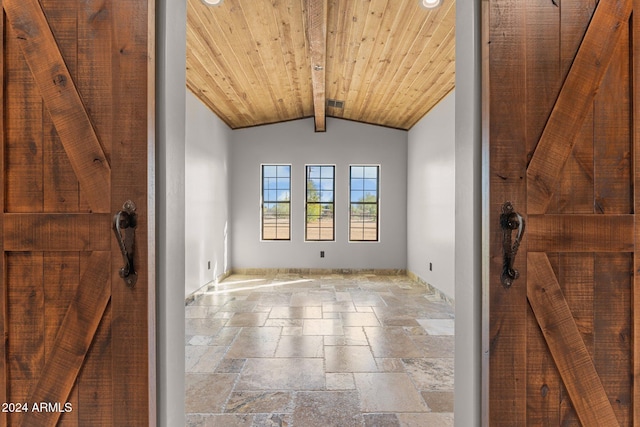 spare room featuring stone tile flooring, visible vents, wooden ceiling, and vaulted ceiling with beams