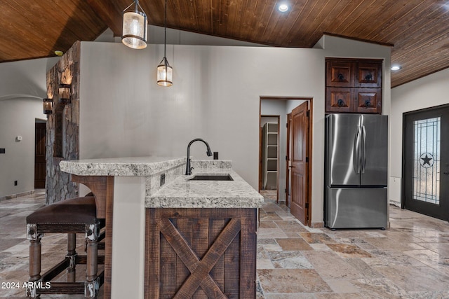 kitchen with dark brown cabinetry, wooden ceiling, freestanding refrigerator, stone tile flooring, and a sink