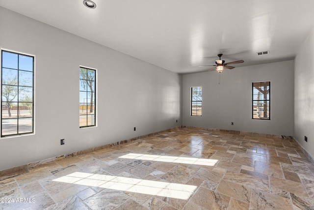 spare room with visible vents, stone tile flooring, and a ceiling fan