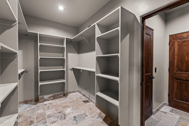 walk in closet featuring stone tile flooring