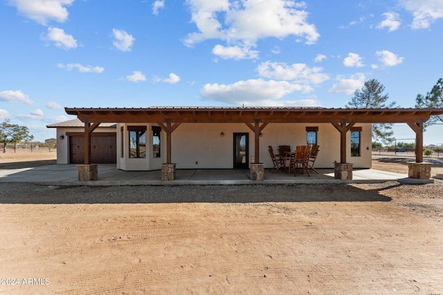 back of property featuring concrete driveway, an attached garage, a patio area, and stucco siding