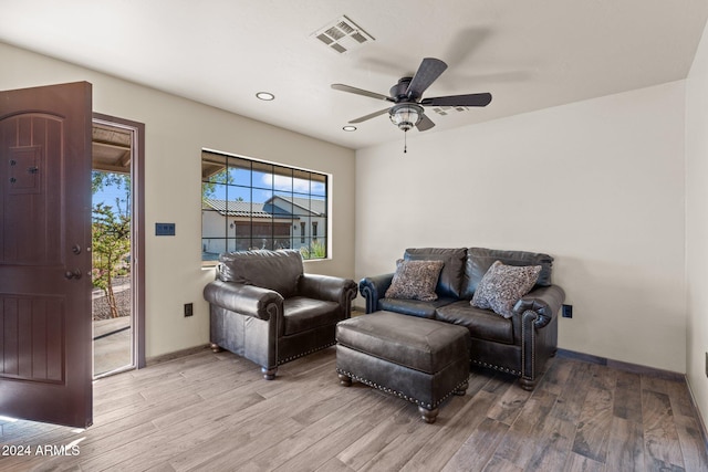 living room featuring a ceiling fan, baseboards, visible vents, and light wood-type flooring