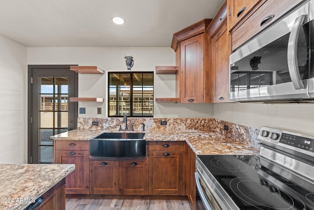 kitchen featuring light stone counters, a sink, stainless steel appliances, and open shelves