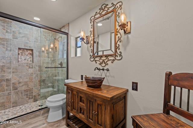 full bathroom with vanity, toilet, wood finished floors, and tiled shower