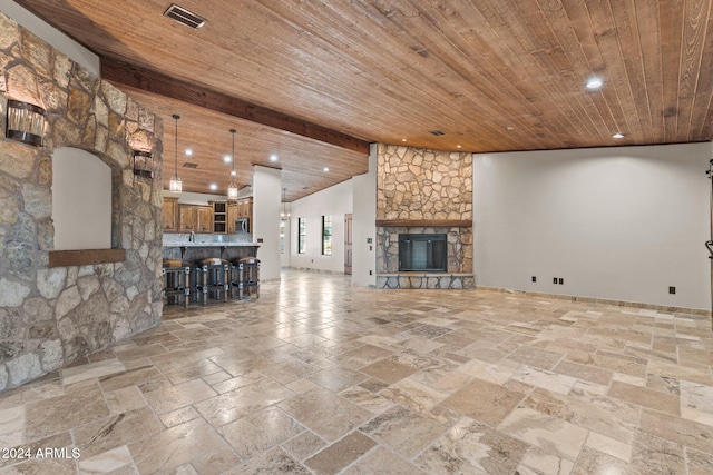 unfurnished living room featuring stone tile floors, visible vents, recessed lighting, a stone fireplace, and wood ceiling