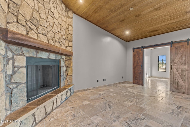 unfurnished living room featuring a barn door, stone tile floors, and wooden ceiling