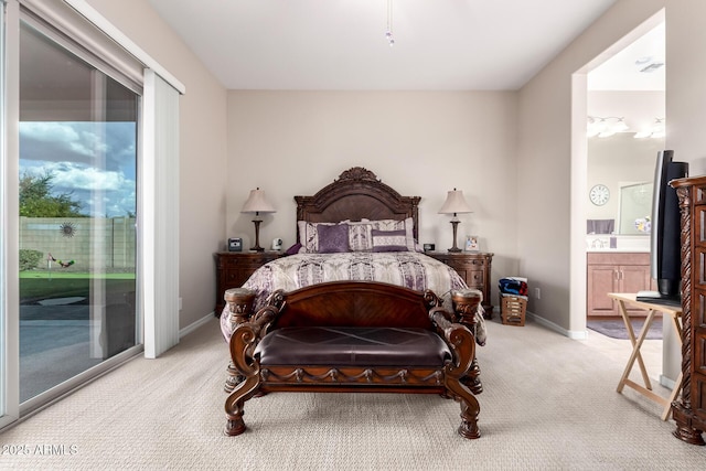 bedroom featuring light colored carpet, access to exterior, and ensuite bath