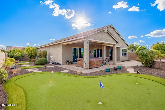 back of property with a hot tub and a patio