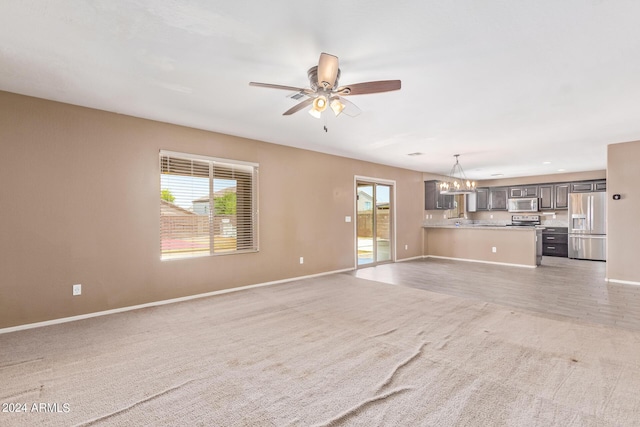 unfurnished living room featuring ceiling fan with notable chandelier and light colored carpet