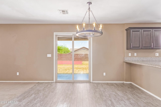 unfurnished dining area featuring light hardwood / wood-style flooring and a notable chandelier