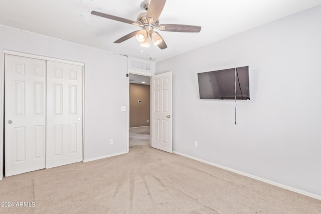 unfurnished bedroom with light carpet, a closet, and ceiling fan