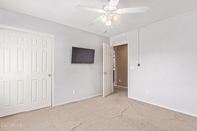 unfurnished bedroom with ceiling fan, a closet, and light colored carpet