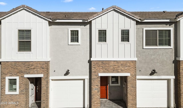 view of front of house featuring brick siding, stucco siding, board and batten siding, and a garage