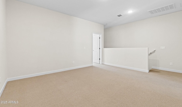 spare room with visible vents, baseboards, and light colored carpet