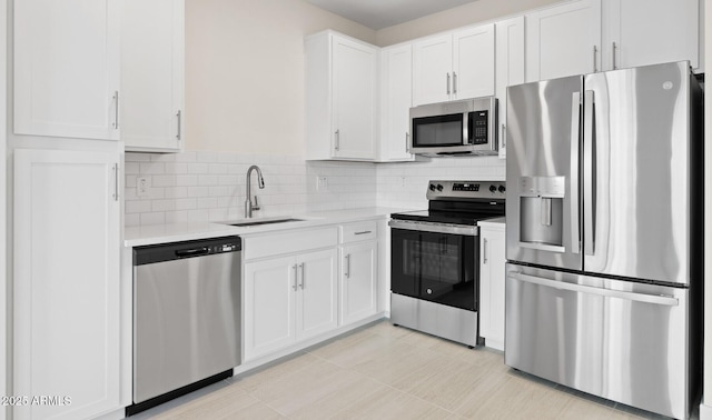 kitchen with a sink, tasteful backsplash, white cabinetry, stainless steel appliances, and light countertops