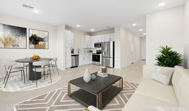 living room with light wood-style floors, recessed lighting, and visible vents