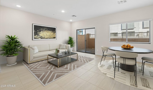 living area with light tile patterned floors, visible vents, recessed lighting, and baseboards