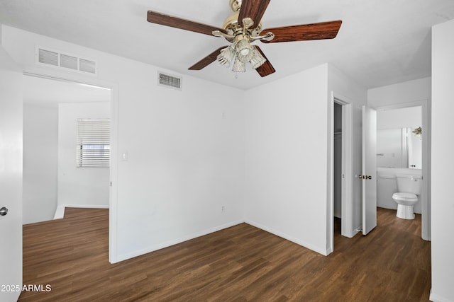 unfurnished bedroom featuring dark wood-type flooring, ceiling fan, ensuite bathroom, and a closet