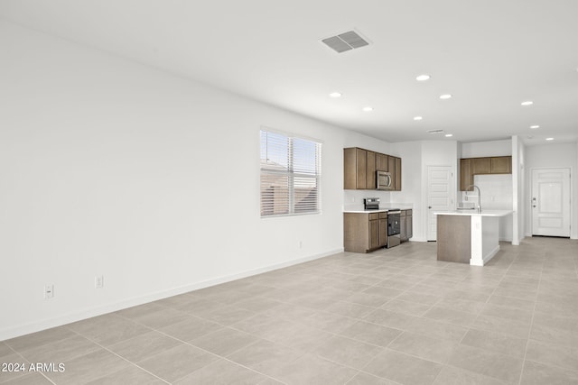 unfurnished living room featuring light tile patterned floors and sink