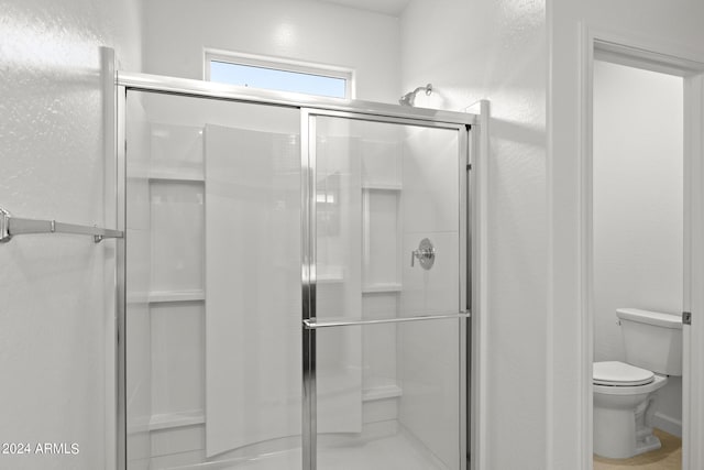 bathroom with toilet and a shower with shower door