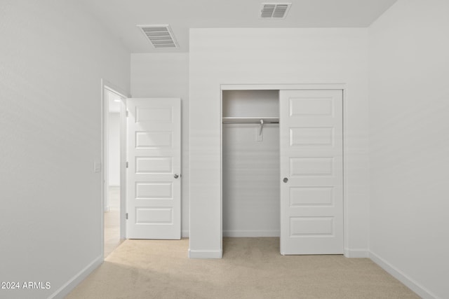 unfurnished bedroom with light carpet and a closet