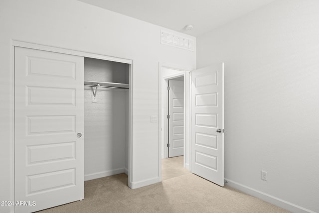 unfurnished bedroom featuring light carpet and a closet