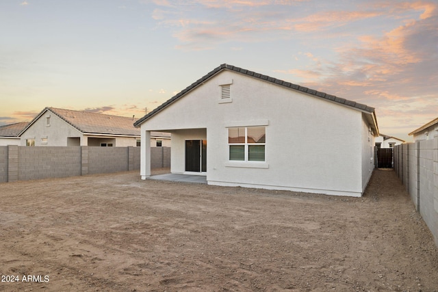 back house at dusk featuring a patio area