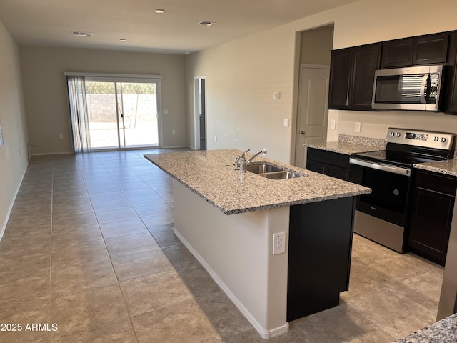 kitchen featuring a kitchen island with sink, appliances with stainless steel finishes, sink, and light stone counters