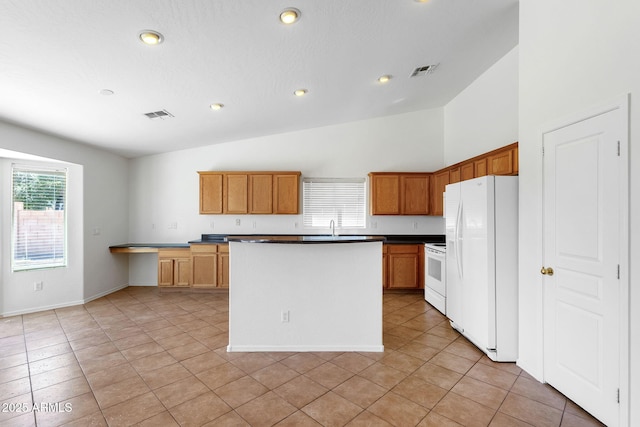 1669 E Santa Fiore St, San Tan Valley, AZ 85140 - kitchen with white appliances, dark countertops, light tile patterned flooring, a center island, and recessed lighting