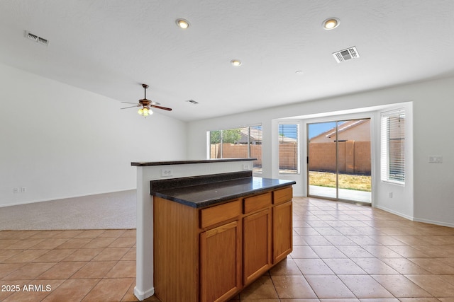 1669 E Santa Fiore St, San Tan Valley, AZ 85140 - kitchen featuring light colored carpet, light tile patterned floors, brown cabinetry, ceiling fan, and baseboards