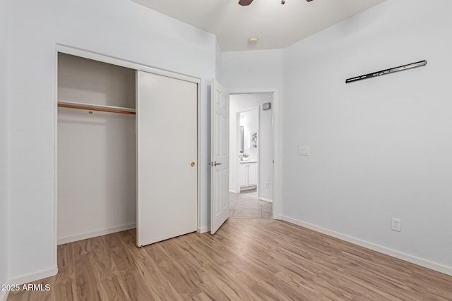 unfurnished bedroom featuring ceiling fan, a closet, and light hardwood / wood-style flooring