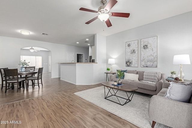 living room featuring ceiling fan and dark hardwood / wood-style floors