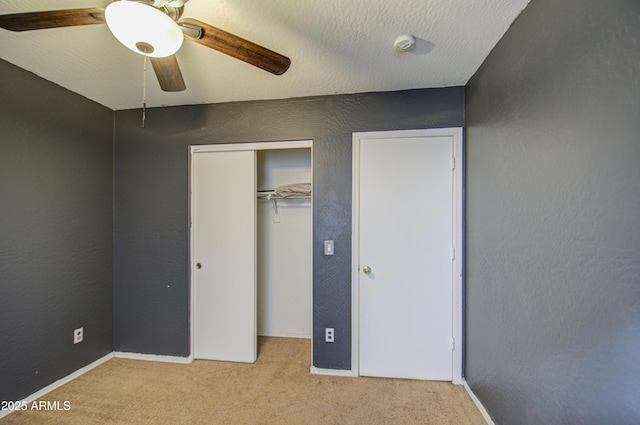 unfurnished bedroom with ceiling fan, light carpet, a closet, and a textured ceiling