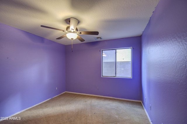 spare room featuring carpet floors, ceiling fan, and a textured ceiling