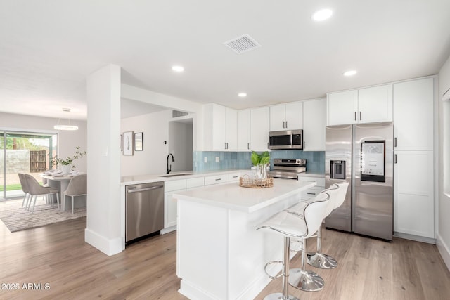 kitchen featuring visible vents, a kitchen island, light countertops, light wood-style flooring, and appliances with stainless steel finishes