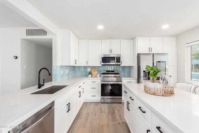 kitchen featuring backsplash, visible vents, appliances with stainless steel finishes, and a sink