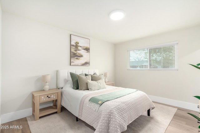 bedroom featuring baseboards and light wood finished floors