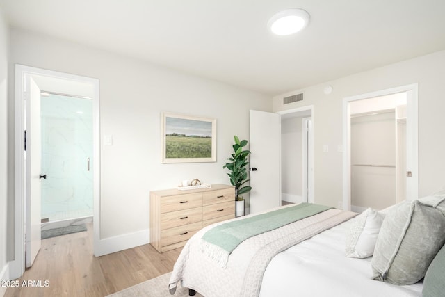 bedroom with visible vents, light wood-style flooring, ensuite bathroom, a closet, and baseboards