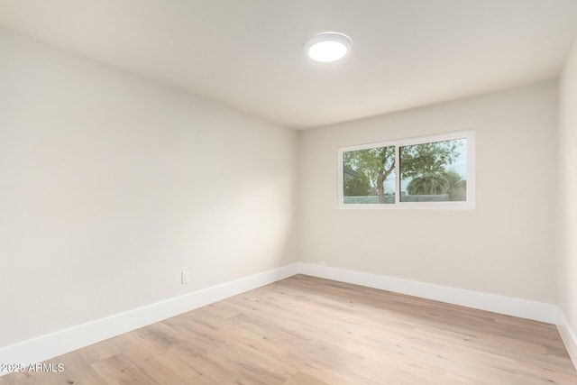 spare room featuring baseboards and light wood finished floors