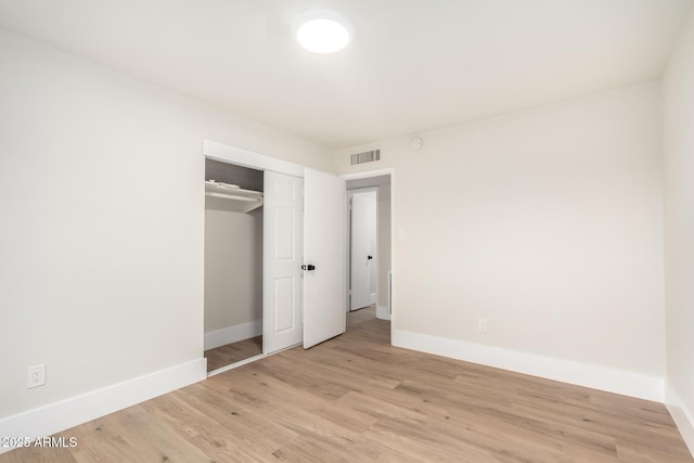 unfurnished bedroom featuring visible vents, baseboards, a closet, and light wood-style flooring