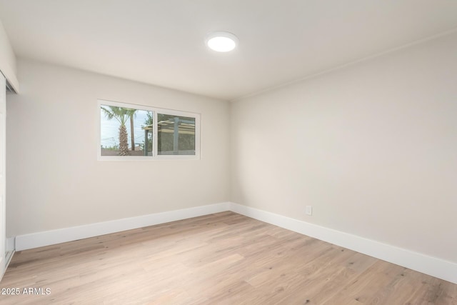 spare room featuring baseboards and light wood finished floors