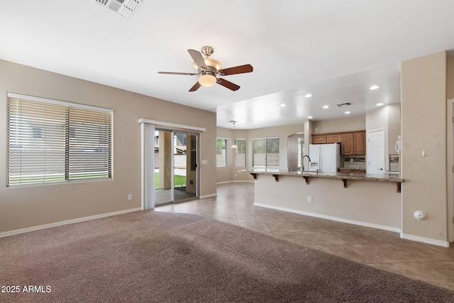2036 E Carob Dr, Chandler, AZ 85286 - unfurnished living room with ceiling fan, light tile patterned floors, baseboards, light carpet, and a sink