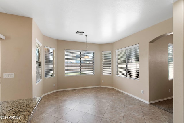 2036 E Carob Dr, Chandler, AZ 85286 - unfurnished dining area featuring light tile patterned floors, arched walkways, and baseboards