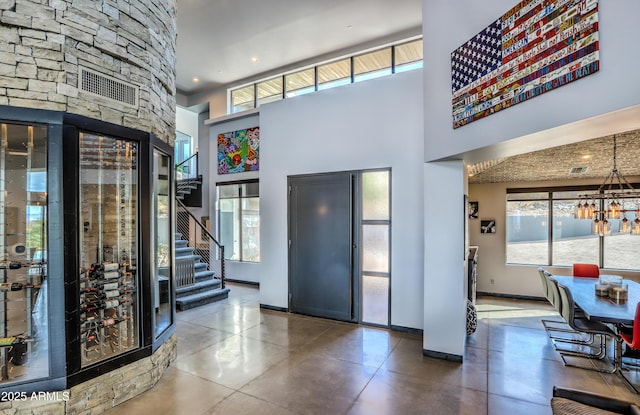 entryway featuring concrete floors, a high ceiling, baseboards, and a notable chandelier