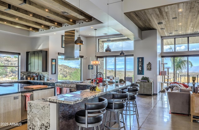 kitchen featuring wall chimney exhaust hood, a high ceiling, dark stone countertops, and tasteful backsplash