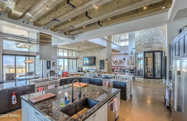 kitchen featuring a sink, a large island with sink, high end refrigerator, and island range hood