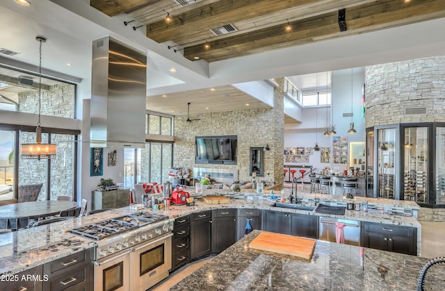 kitchen featuring a healthy amount of sunlight, stone counters, island exhaust hood, and a sink